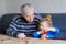 Beautiful toddler girl and grandfather playing together pictures memory table cards game at home. Cute child and senior