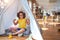 Beautiful toddler wearing glasses and unicorn diadem sitting on the floor at kindergarten looking confident with smile on face,