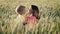 Beautiful touching scene of toddler son kissing mom in fresh wheat field. Happy mother and baby boy embracing. Family