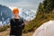 Beautiful tourist girl standing near a tent on a background of forest snow-capped mountains