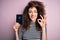 Beautiful tourist woman with curly hair and piercing holding australia australian passport id doing ok sign with fingers,