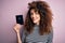 Beautiful tourist woman with curly hair and piercing holding australia australian passport id with a happy face standing and