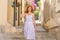 Beautiful tourist woman with hat and dress walking in cozy italian street in Cefalu, Sicily, Italy