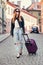 Beautiful tourist woman traveling in Europe and walking with suitcase on city street. Concept photo of people travel.