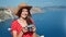 Beautiful travel woman in hat posing holding camera at sea landscape background at sunny summer day