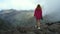 Beautiful traveler woman in a pink sweater stands on the edge of a cliff and enjoys the view of the Masca Valley on the