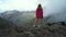 Beautiful traveler woman in a pink sweater stands on the edge of a cliff and enjoys the view of the Masca Valley on the