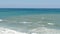 Beautiful tricolor sea with different shades of turquoise blue and dark green with waves and white foam on it