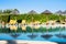 Beautiful tropical beach front hotel resort with swimming pool, umbrella, sun-loungers and palm trees at sunny day