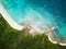 Beautiful tropical forest meets ocean with white coral beach, and rocks. Drone image from high above, birds eye view.