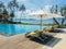 Beautiful tropical swimming pool in hotel or resort with umbrella, coconuts tree sun-loungers, palm trees with infinity pool view