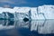 Beautiful turquoise iceberg wall with texture and cave in Antarctica reflecting  in calm water