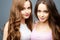 Beautiful twins young women in casual clothes over grey background. Beauty fashion portrait