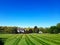 beautiful two story country home with a large manicured lawn and landscaping in the front yard. Landscape under a blue sky