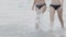 Beautiful two young asian woman in bikini walking and splashing water at beach.