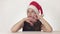 Beautiful unhappy girl teenager in a Santa Claus hat emotionally expresses a pensive sadness on white background stock