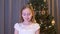 Beautiful upset girl standing near christmas tree and crying indoors