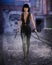 Beautiful urban fantasy assassin woman walking along a seedy dydtopian future street holding gun with silencer in each hand. 3D