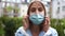 Beautiful urban girl puts on a medical mask. Close outdoor portrait. Coronavirus pandemic, covid-19 lockdown