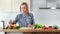 Beautiful vegan woman cooking fresh salad and trying vegetables looking at camera medium shot