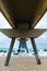 Beautiful vertical shot of a beach from below a wooden bridge