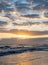 Beautiful vertical shot of sea waves under a cloudy sky at sunset