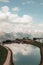 Beautiful vertical view of a reflective lake in the middle of a hill with walking people on a road