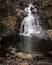 Beautiful vertical view of the waterfall flowing over the rocky cascade