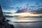 Beautiful vibrant sunrise sky over calm water ocean with lighthouse and harbor wall