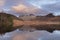 Beautiful vibrant Winter sunrise over Blea Tarn in Lake District with snow capped Langdale Pikes in distance