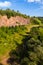 A beautiful view from above on the dirt road going between the forest and a sheer rocky hill