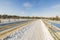 Beautiful view of architecture winter landscape. Snowy road passing through bridge on blue sky background.