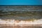 Beautiful view of the Baltic sea ebb and flow waves on a sandy beach under blue sky