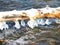 Beautiful view of branch with icicles in clear water of winter lake