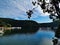 Beautiful view of a calm creek with reflections of blue sky, mountains and trees on water