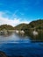 Beautiful view of a calm creek with reflections of blue sky, mountains and trees on water