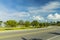 Beautiful view of city landscape. Asphalt road and green tropical trees on blue sky with white clouds background. Key West.