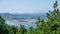 Beautiful view of the city and two sea bays and high mountains in the haze on the horizon through the dense branches of pine trees