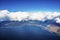 Beautiful view of clouds covering landscape by seaside against blue sky