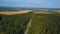 Beautiful view of the field from the drone. Clip. A huge Russian green forest with a road, a field beyond, a clear blue
