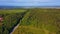 Beautiful view of the field from the drone. Clip. A huge Russian green forest with a road, a field beyond, a clear blue