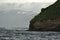 Beautiful view of a flock of puffins flying over the sea near the hill in Iceland