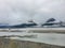 Beautiful view of the foggy mountains in Beluga Point with a river and a branch on the ground