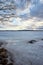 Beautiful view of a frozen lake and stones on a shore on a cloudy day