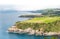 A beautiful view from a height of the ocean shore with green sloping fields, steep cliffs against the backdrop of an approaching