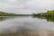 Beautiful view of a lake with many trees and a gray sky and reflection in the water