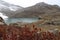 Beautiful view of lake with red grass and glaciers on mountain under cloudy sky