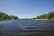 Beautiful view on lake on summer day. Dark lake water surface, green tall trees and blue sky. Sweden,