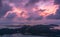 Beautiful view of a lake surrounded by hills under a cloudy pink sky at sunset