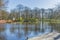 Beautiful view of a lake with trees, orange and pink flowers with a fountain